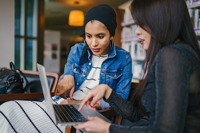 Two women with a laptop discussing mistakes small business owners make